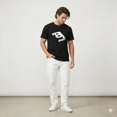Black t-shirt with a white logo on a hanger against a white wall with plants.