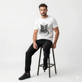 Man sitting on a stool wearing a white t-shirt with a graphic design and text.