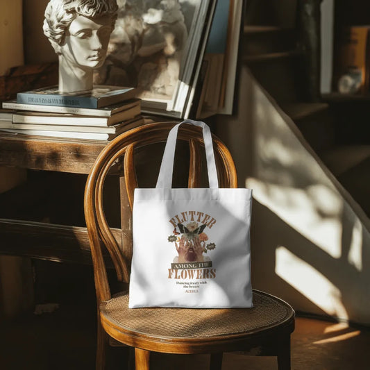 White tote bag with graphic design on a wooden chair in a warm, sunlit room.
