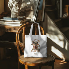 White tote bag with graphic design on a wooden chair in a warm, sunlit room.