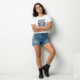 Woman wearing a white t-shirt with graphic design, blue denim shorts, and black boots on a white background