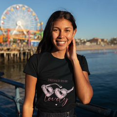 Woman wearing a black t-shirt with a quote, standing by water with a Ferris wheel in the background