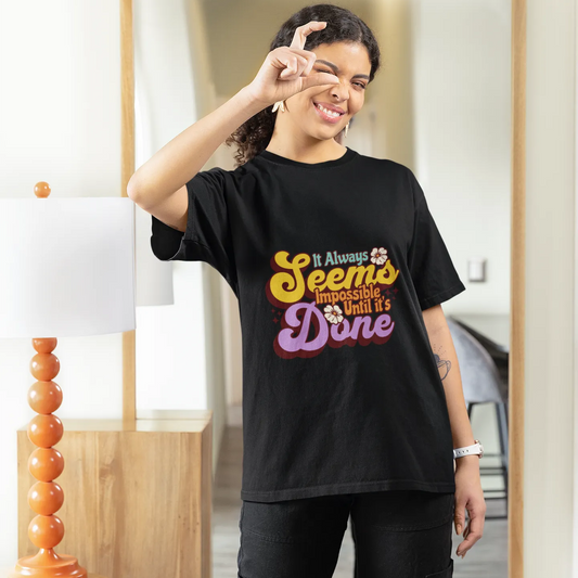 Person wearing a black t-shirt with colorful text, standing in front of a mirror.