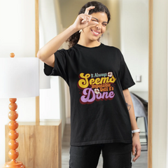 Person wearing a black t-shirt with colorful text, standing in front of a mirror.