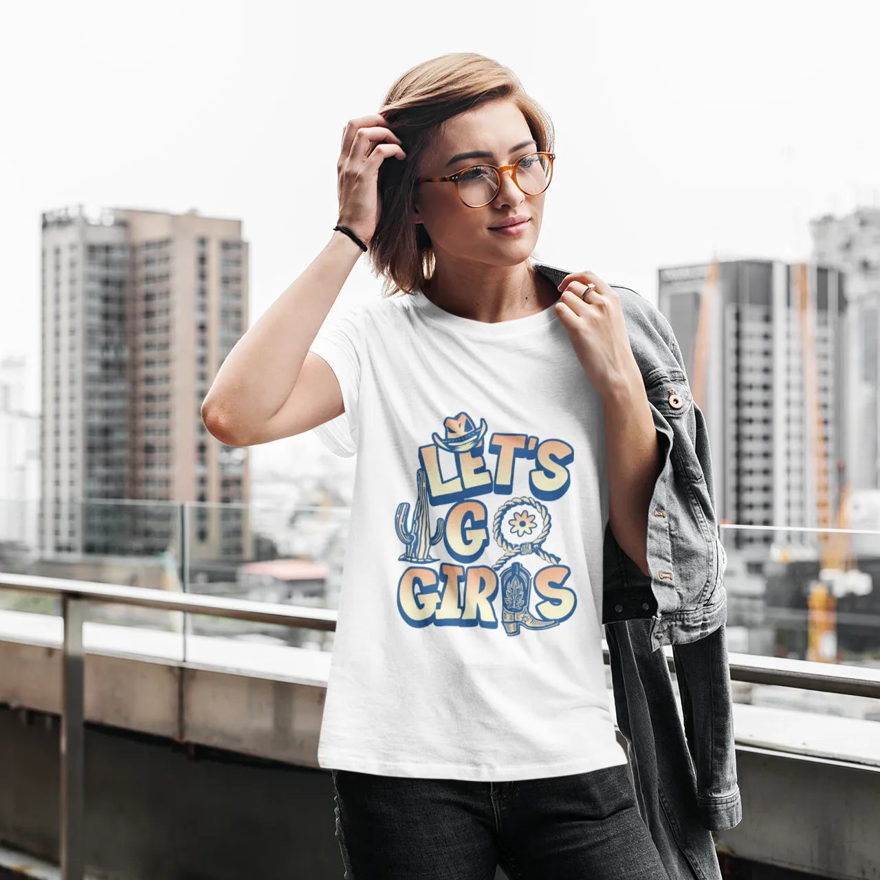 Woman wearing a white t-shirt with colorful text, standing on a rooftop with cityscape background