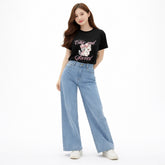Woman wearing a black t-shirt with a graphic and text, paired with light blue jeans on a white background