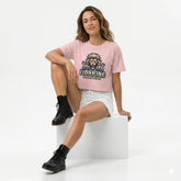 Person wearing a pink t-shirt with a lion graphic and text against a brick wall.