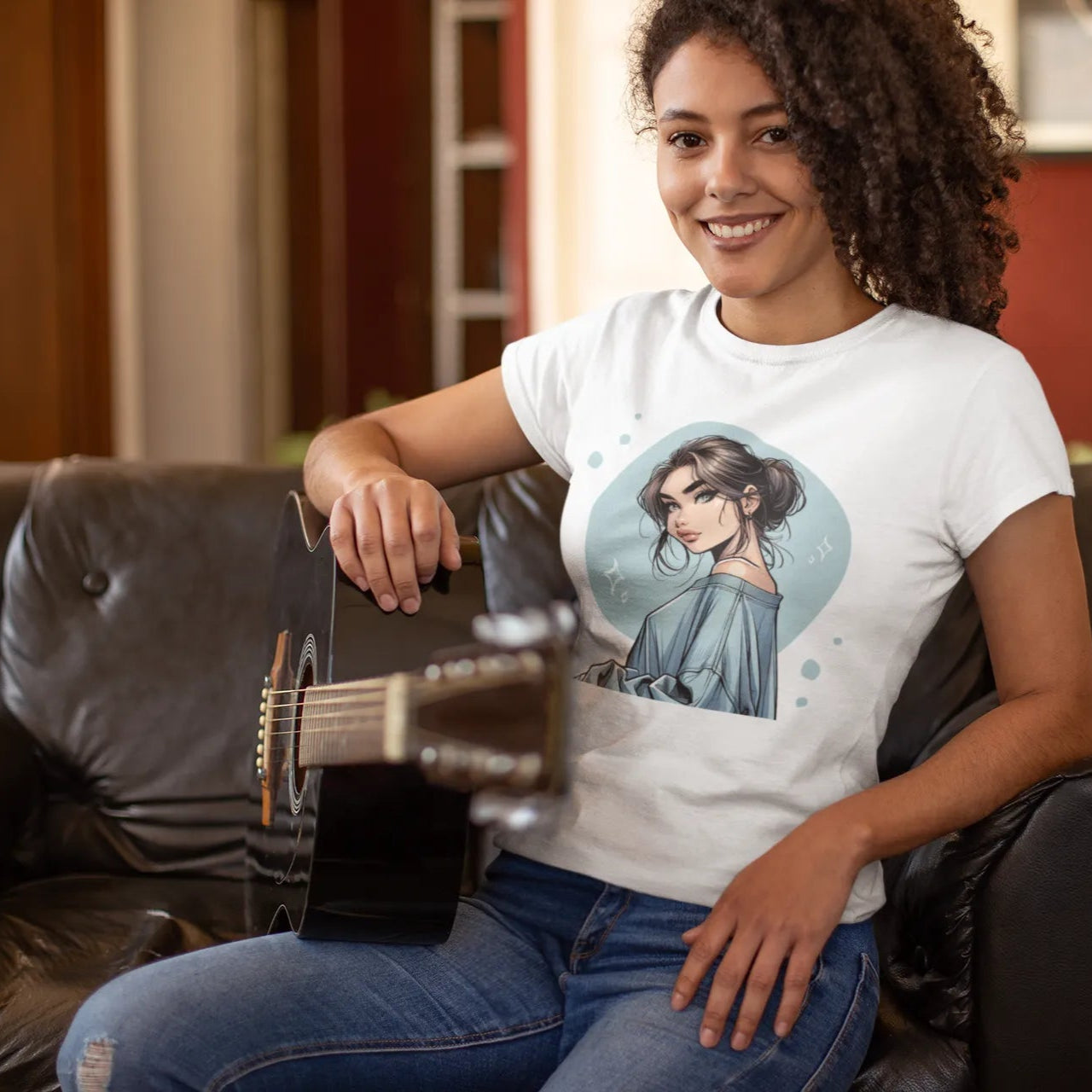 Woman sitting on a couch wearing a t-shirt with a graphic design, holding a guitar.