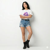 Woman wearing a white t-shirt with a graphic design, blue denim shorts, and black boots on a plain background