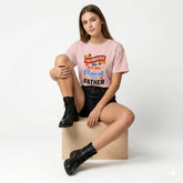 Woman wearing a pink t-shirt with text, sitting on a box against a white background