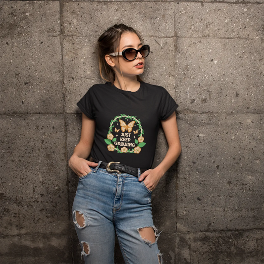 Woman wearing a black t-shirt with a graphic design and ripped jeans against a gray concrete wall.