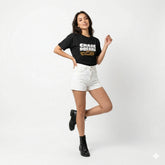 Woman wearing a black t-shirt with text and white shorts on a white background