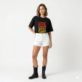 Person wearing a black t-shirt with 'Give Your Best Shot' text, white shorts, and black boots on a white background