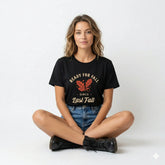 Woman wearing a black t-shirt with 'Ready for Fall since Last Fall' text and sitting on a white background