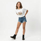 Woman wearing a white t-shirt with a graphic design and denim shorts on a white background