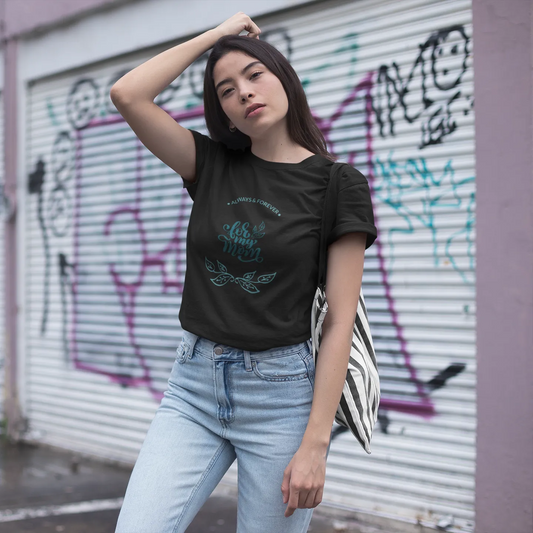 Woman wearing a black t-shirt and light blue jeans in front of a graffiti-covered wall.
