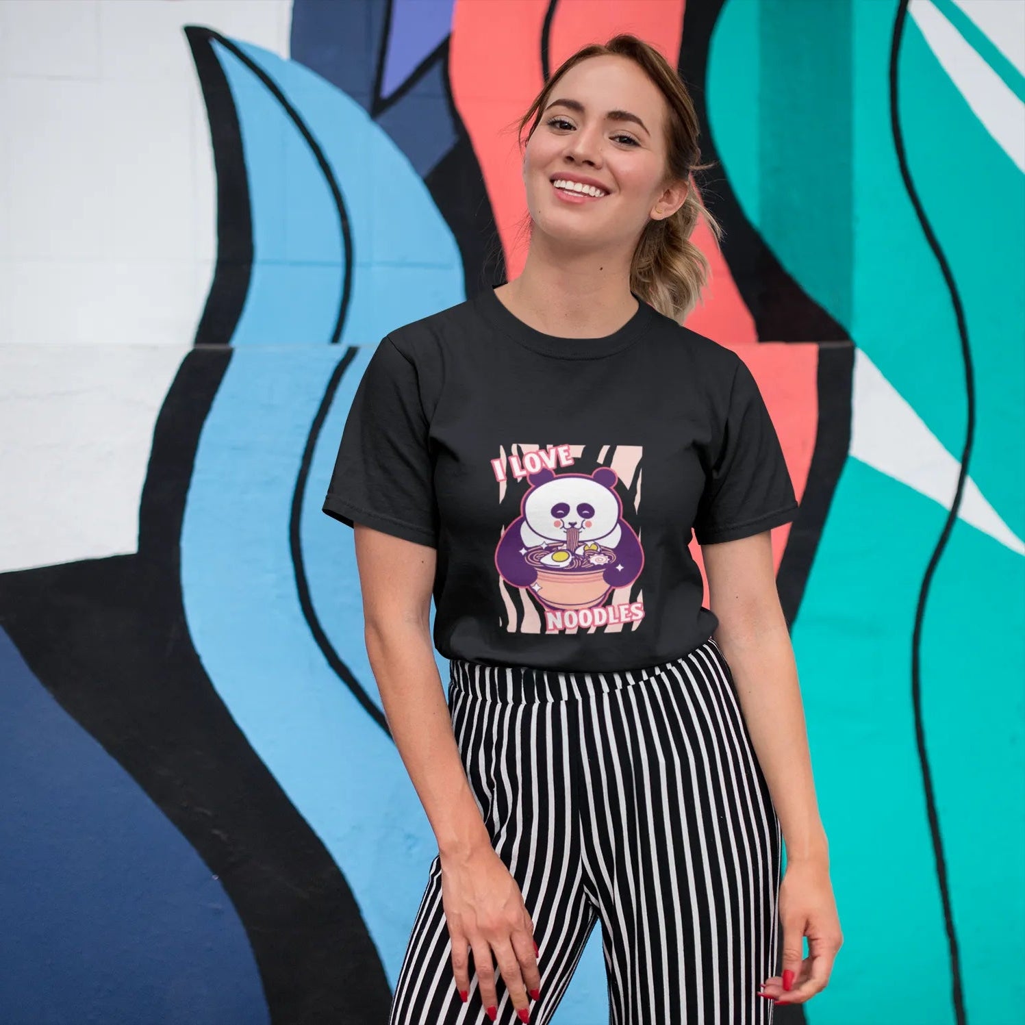 Woman wearing a black t-shirt with a graphic design in front of a colorful abstract wall.