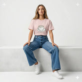 Woman wearing a pink t-shirt with a coffee cup design in a dimly lit room.