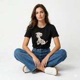 Woman wearing a black t-shirt with a dog graphic and blue jeans sitting on a white background