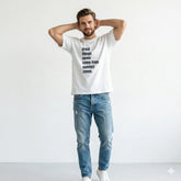 Man wearing a white t-shirt with a motivational quote and blue jeans on a light gray background