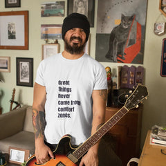 Man holding a guitar in a room with framed pictures on the wall