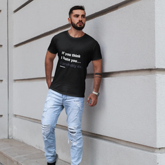 Man wearing a black t-shirt with text and light blue jeans standing against a white wall.