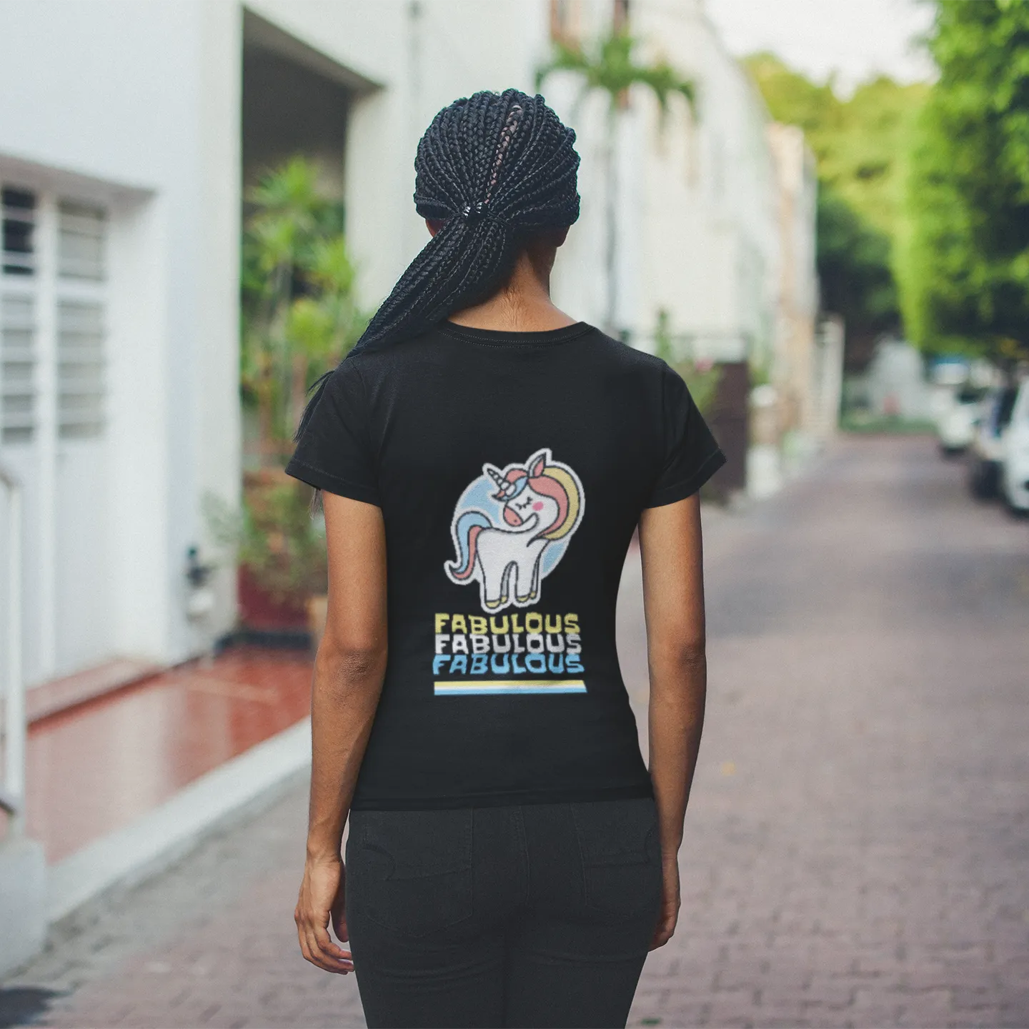 Person wearing a black t-shirt with a unicorn graphic and text on a street.