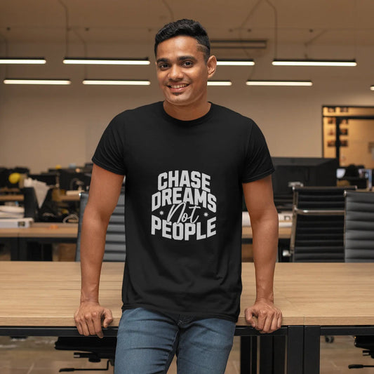 Man wearing a black t-shirt with 'Chase Dreams Not People' text in an office setting