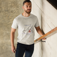 Man wearing a gray t-shirt with a graphic design, standing against a textured wall.