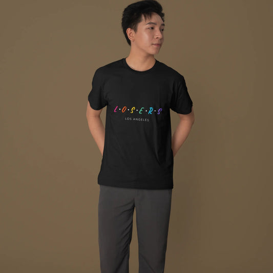 Person wearing a black t-shirt with colorful text on a brown background