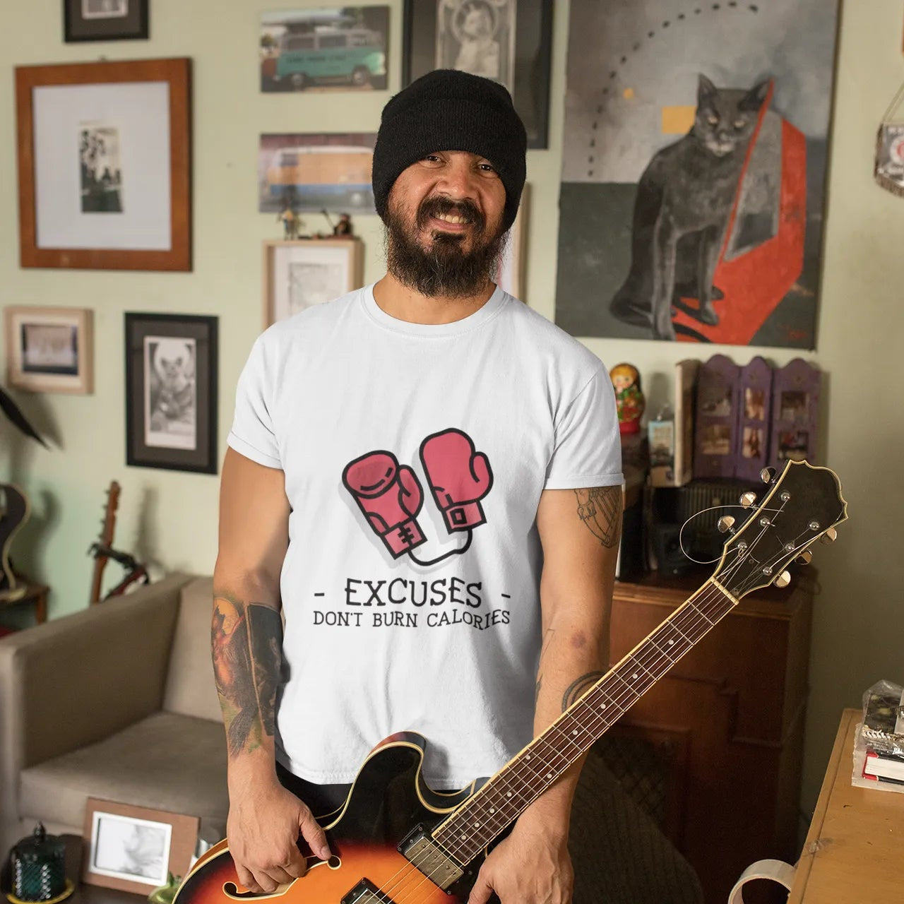 Man holding a guitar in a room with various decorations on the wall