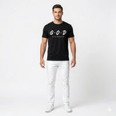 Man wearing a black t-shirt with 'GOD' printed on it at the beach.