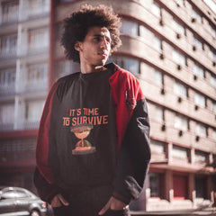 Person wearing a black and red jacket with text and graphic design, standing in front of a building.