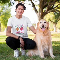 Man in a white t-shirt with colorful graphics sitting on grass with a golden retriever dog.