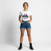 Woman wearing a white t-shirt with colorful text and design, standing against a plain background