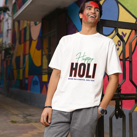 Person wearing a 'Happy Holi' t-shirt in front of a colorful mural.