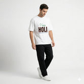 Man wearing a white t-shirt with 'Happy Holi' text on a plain background