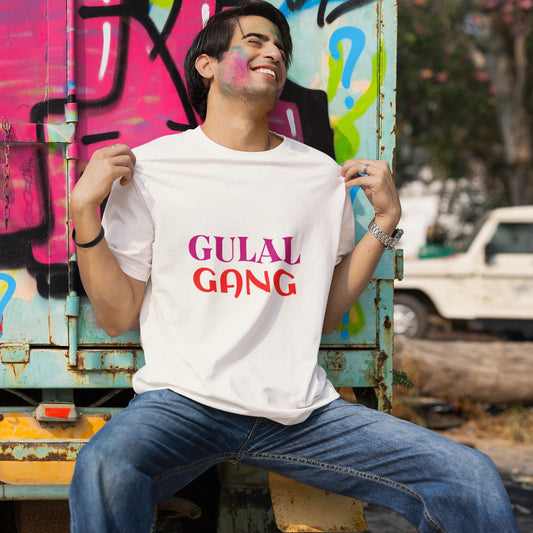 Person wearing a 'GULAL GANG' t-shirt sitting against a graffiti-covered wall.