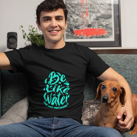 Man wearing a black t-shirt with green text sitting on a couch with a dog.