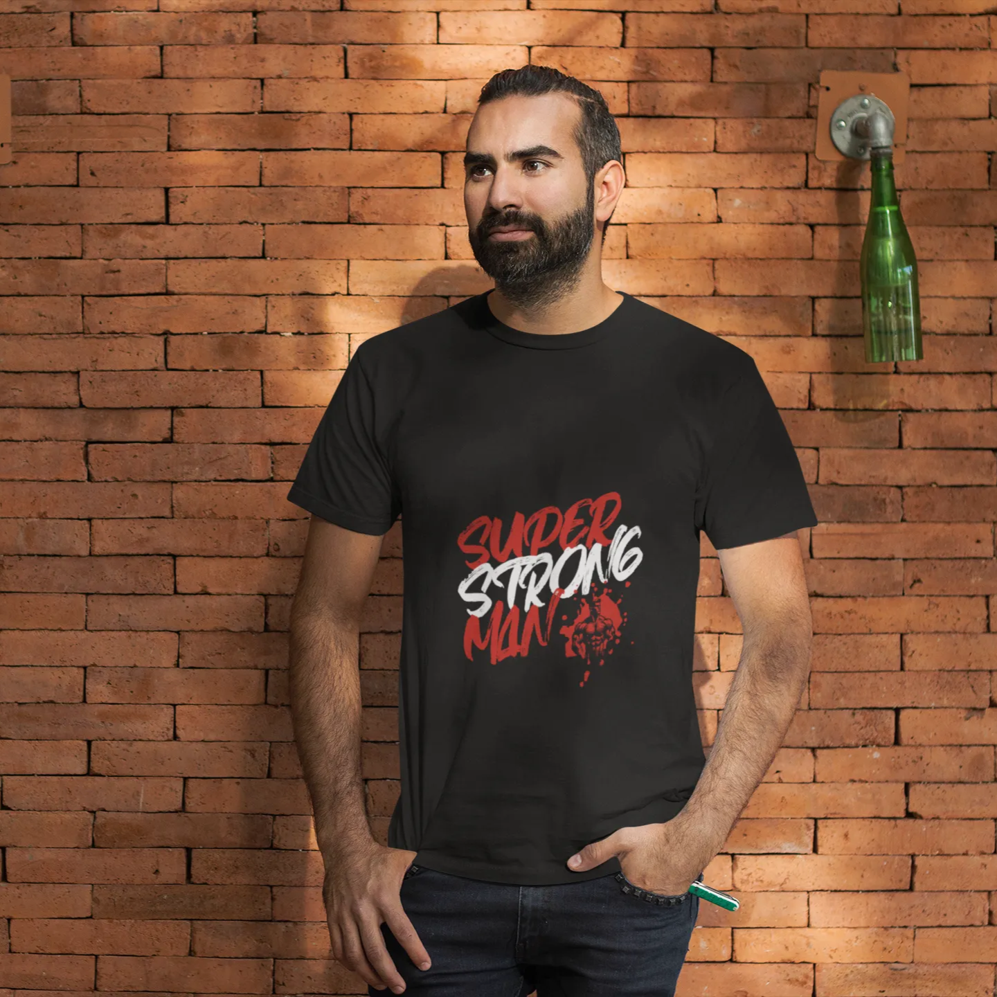 Man wearing a black t-shirt with red and white text against a brick wall.