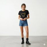 Woman holding a coffee cup wearing a black t-shirt with a heart design and text.