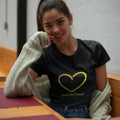 Woman wearing a black t-shirt with a yellow heart design, sitting at a table.