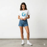 Woman wearing a white t-shirt with a graphic design and denim shorts on a plain background