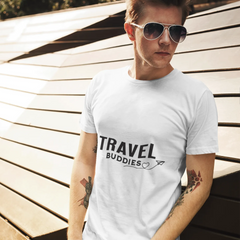 Person wearing a white t-shirt with 'TRAVEL BUDDIES' text, standing outdoors.