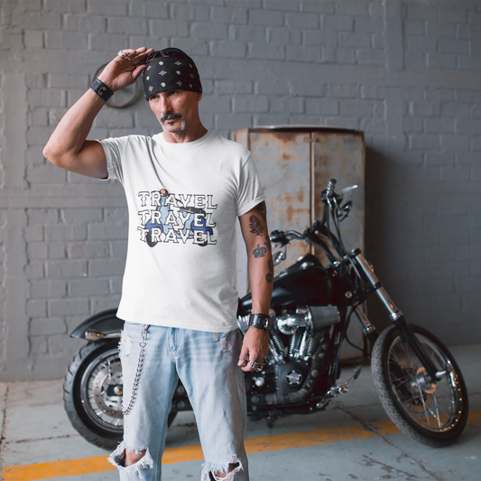 Man wearing a 'Travel Travel Travel' t-shirt standing next to a motorcycle in an indoor setting.