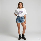 Woman wearing a white t-shirt with text and denim shorts on a gray background