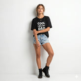 Person wearing a black t-shirt with text and denim shorts on a white background