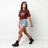Woman wearing a maroon t-shirt with 'Daddy's Princess' text, denim shorts, and black boots on a white background