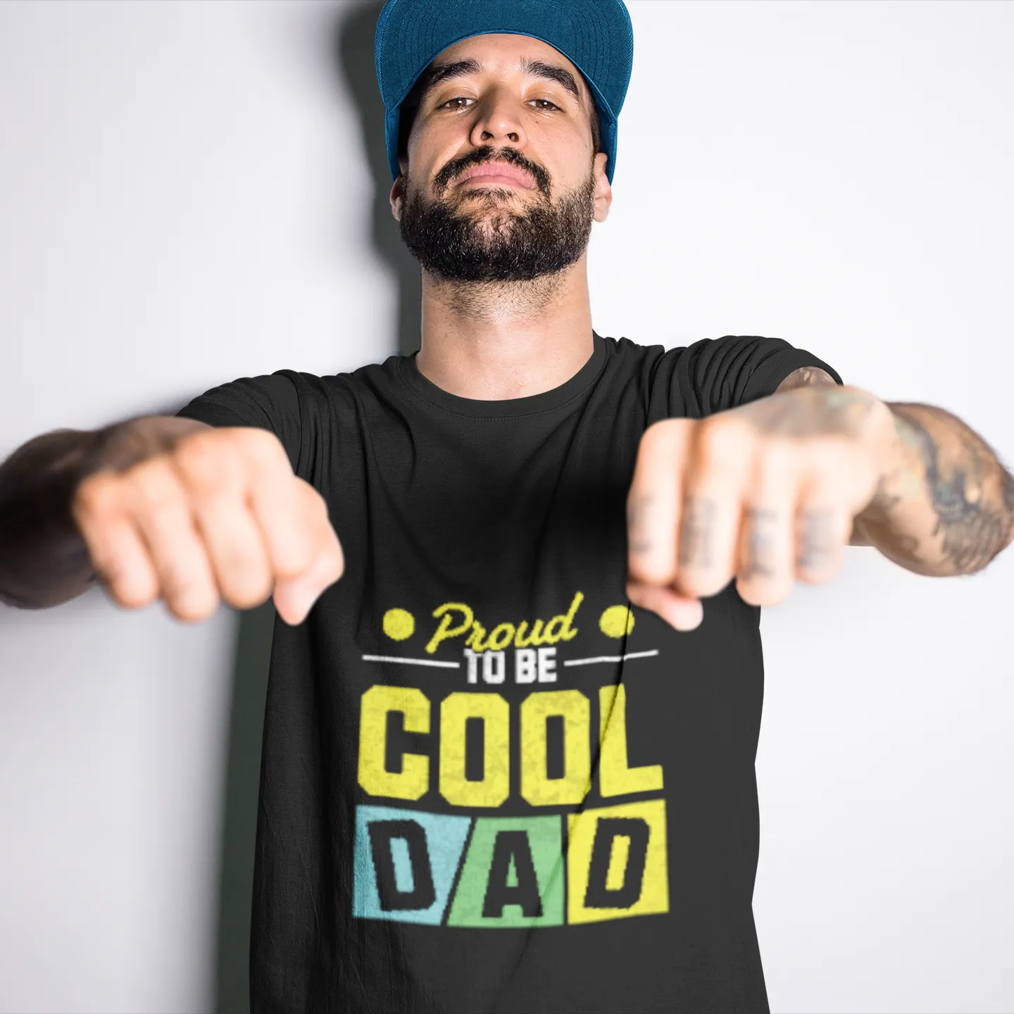Man wearing a black t-shirt with 'Proud to be Cool Dad' text, pointing forward against a white background