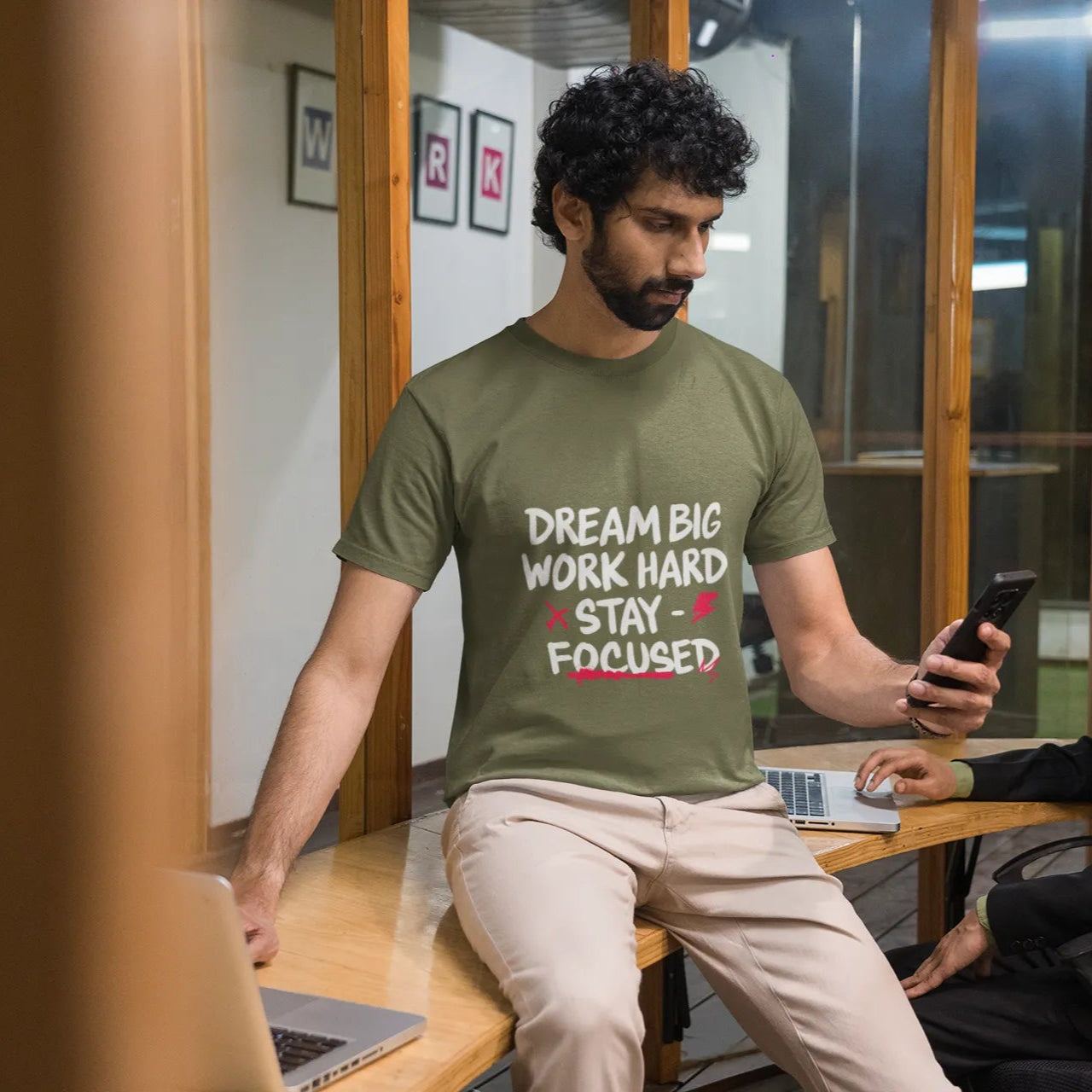 Man wearing a green t-shirt with motivational text in an office setting